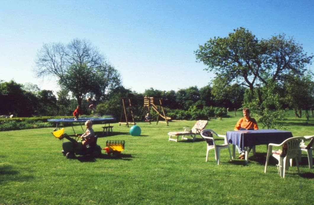 Hof-Garten mit Spielgeräten und Familie am Gartentisch bei Bauer Höper