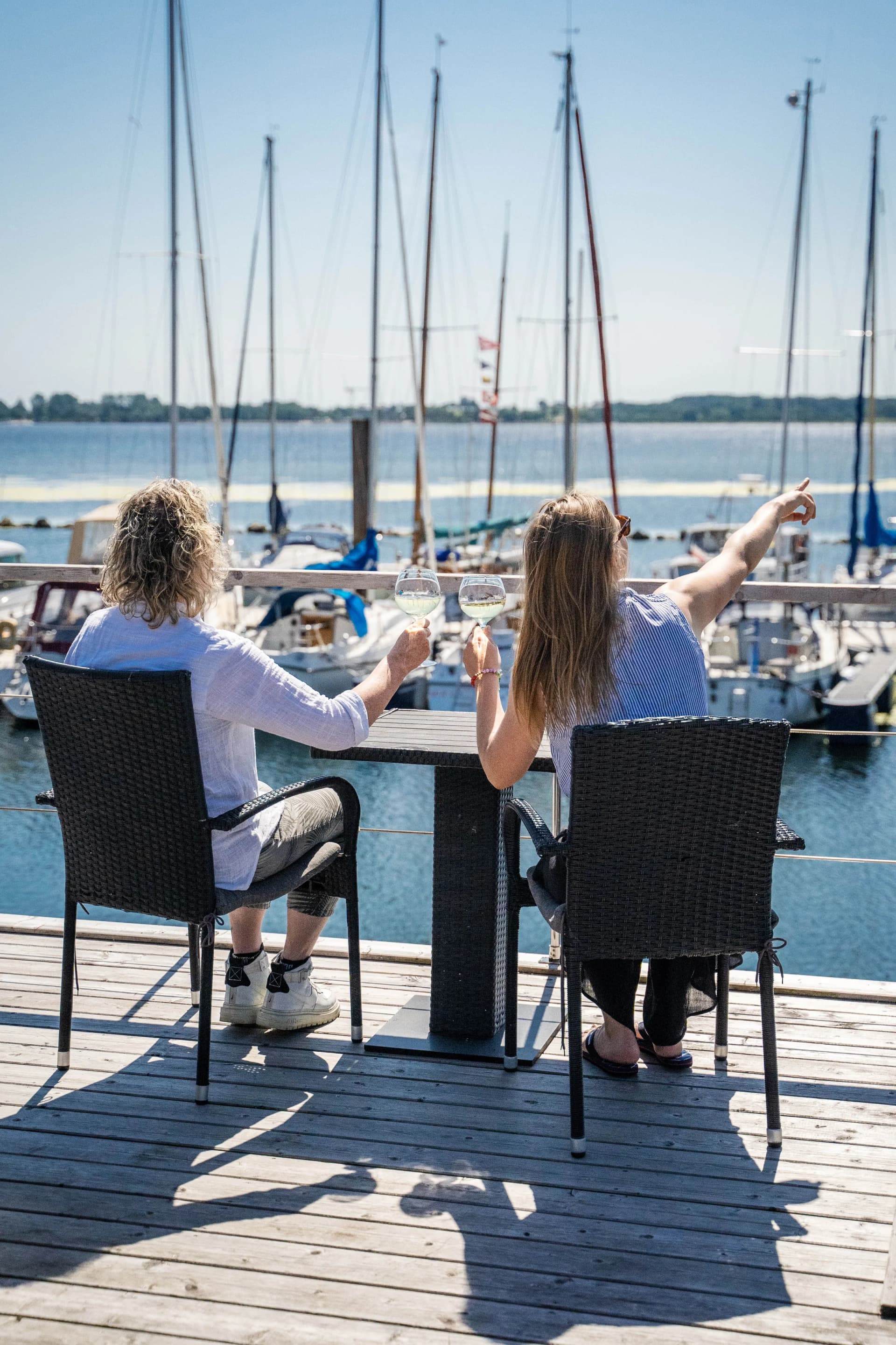 Pärchen mit Wein auf einer Hausboot-Terrasse im Ostseehafen, Huus und Meer