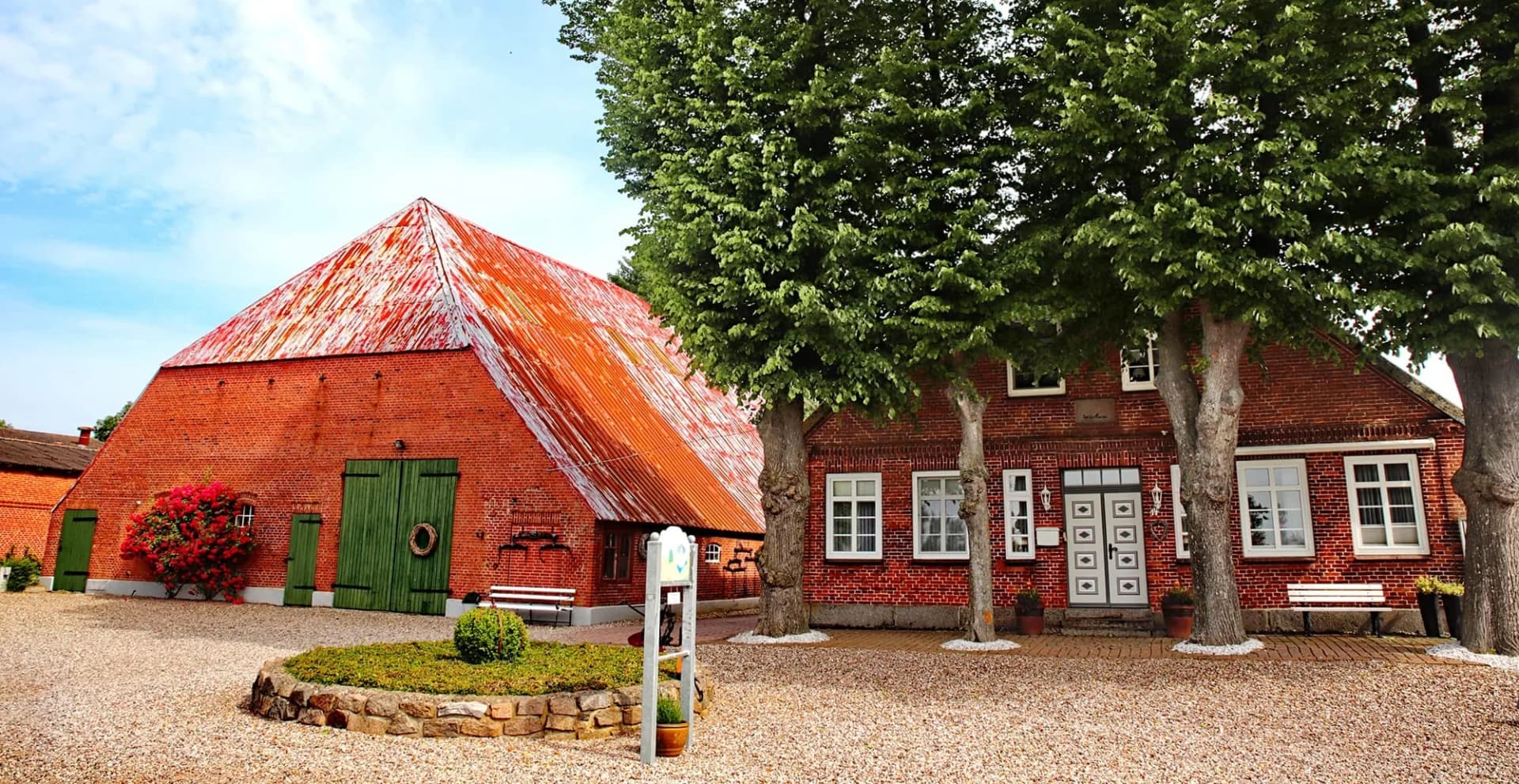 Rotes Backsteinhaus des Landhaus Henrici mit Scheune und hohen Linden in Schlagsdorf auf Fehmarn